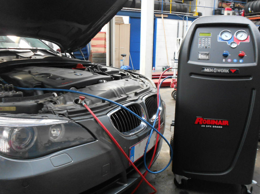 Technicus buigt zich over de motorruimte voor een airco-nazicht
